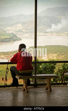 Man sit bench edge valley watch look observe magnificent stunning watercourse Mekong River Huay Xai Laos Southeast Asia Stock Photo