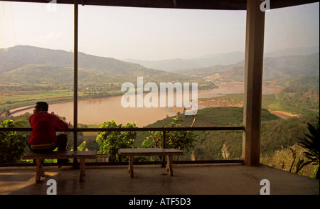 Man sit bench edge valley watch look observe magnificent stunning watercourse Mekong River Huay Xai Laos Southeast Asia Stock Photo