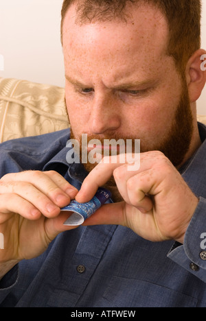 angry young man destroying credit debit bank card to avoid debt and better manage finances Stock Photo