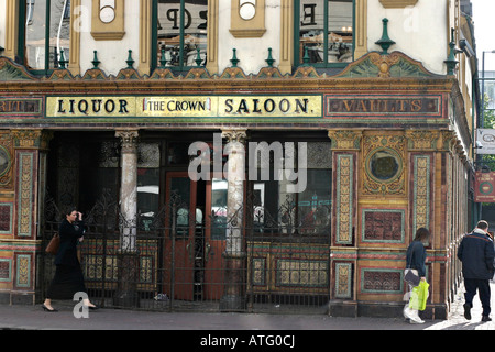 The Crown Saloon. The lower front facade of the famous Belfast landmark of Crown Liquor Saloon Bar Pedestrians walk by Stock Photo