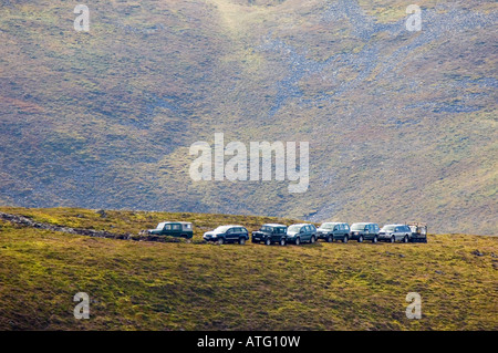 Four wheel drive vehicles belonging to a shooting party on a grouse moor Stock Photo