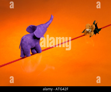 Toy elephant walking on a rope towards a flower. Concept of movement, sustainable development, precision and sense of purpose Stock Photo