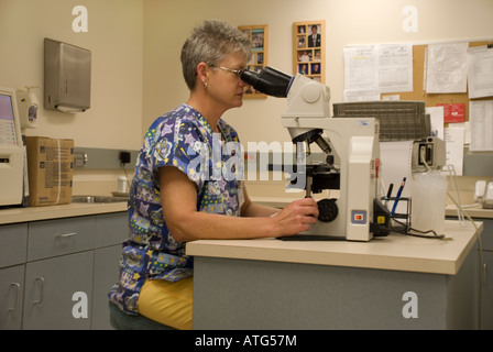 Hospital lab technician looking through microscope Stock Photo
