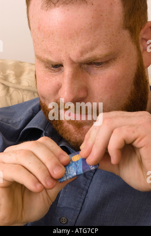 angry young man destroying credit debit bank card to avoid debt and better manage finances Stock Photo