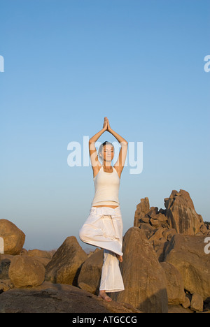 Woman in yoga pose by rocks Stock Photo