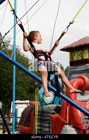 Young boy on bungee bounce swings at safety harness and ropes Stock Photo