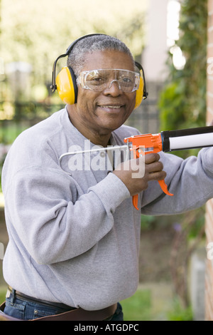 African American Man Using a Caulking Gun Stock Photo