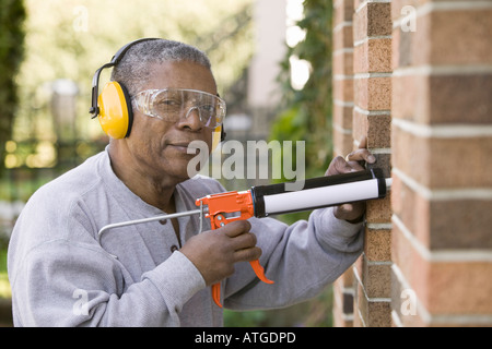 African American Man Using a Caulking Gun Stock Photo