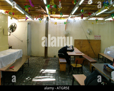 Orthodox Jew sleeping inside inside a traditional wooden sukkah or succah temporary hut constructed for use during the week-long Jewish festival of Su Stock Photo