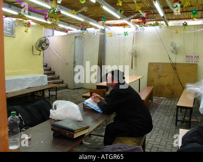 Orthodox Jew inside a traditional wooden sukkah or succah temporary hut constructed for use during the week-long Jewish festival of Sukkot or Sukkoth Stock Photo