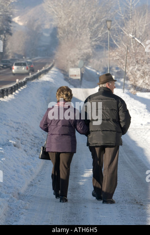 Elderly couple walking on snow covered road Stock Photo