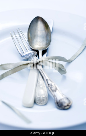 Vintage knives and forks shot on white china plate Stock Photo