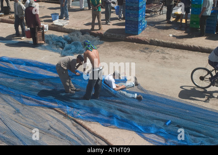 Three men mending fishing nets essaouira Stock Photo