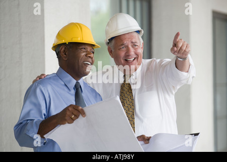 Two engineers discussing a blueprint and smiling Stock Photo