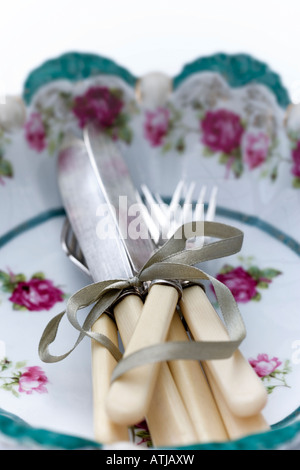 Vintage cutlery tied with green ribbon in a vintage floral china bowl Stock Photo