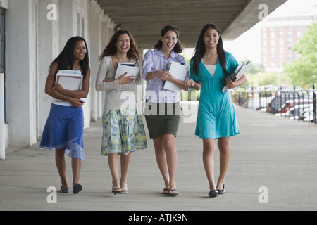 Four teenage girls holding books and hanging out in the school campus Stock Photo