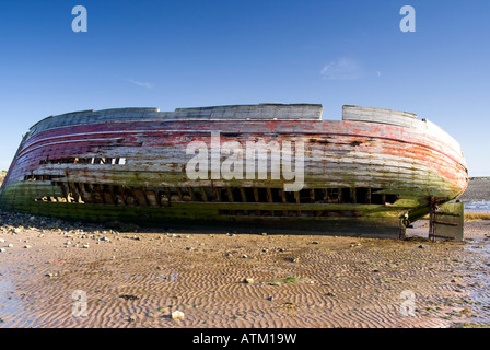 the old hull of a fishing boat beached on its side Stock Photo