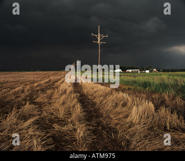 Black skies over telegraph poles and farm buildings after a tornadic storm rural Kansas USA Stock Photo