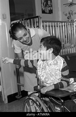 Nurse with severely disabled child in a wheelchair in New York City Stock Photo