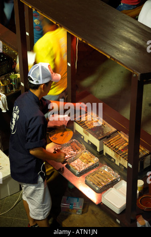 Kobe Japan Japanese man cooking chicken on a skewer Stock Photo