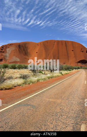 Famous tourist attraction Ayers rock Uluru and the circular ring road deserted in late afternoon sun Australia Stock Photo