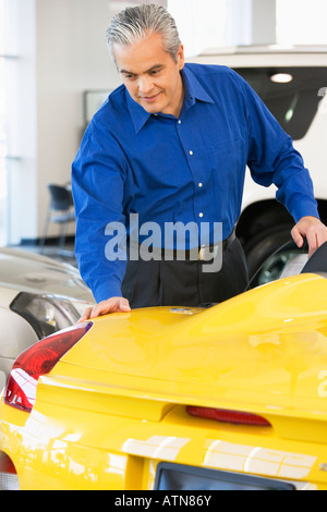 Hispanic car salesman looking at new car Stock Photo