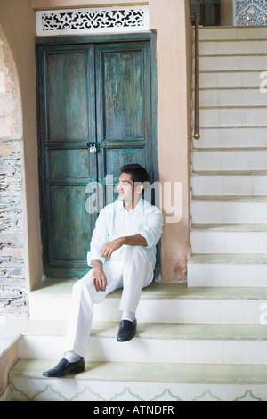 Young man sitting in front of a door Stock Photo