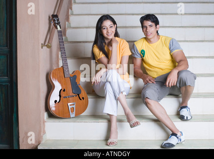 Portrait of a young couple sitting on a staircase and smiling Stock Photo