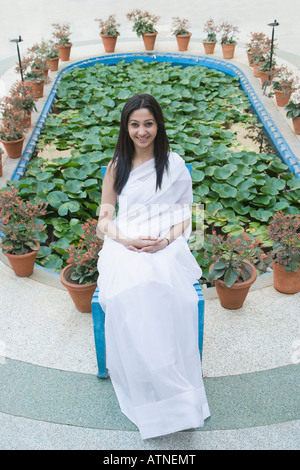 Portrait of a young woman sitting on a stool and smiling Stock Photo