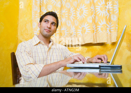Young man using a laptop and thinking Stock Photo