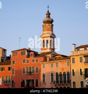 Venice, Veneto, Italy. Bell-tower of the Chiesa di San Bartolomeo rising above colourful mansions, sunset. Stock Photo