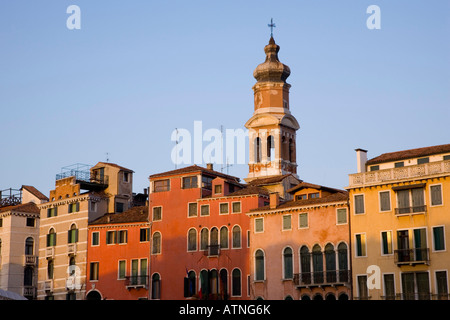 Venice, Veneto, Italy. Bell-tower of the Chiesa di San Bartolomeo rising above colourful mansions, sunset. Stock Photo
