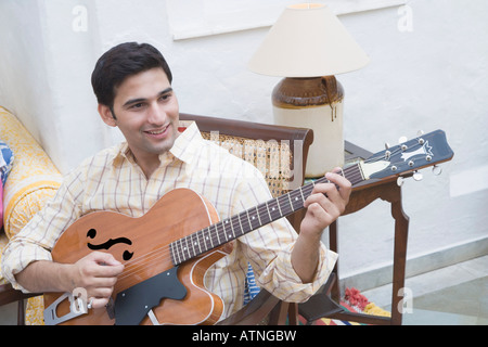Young man playing a guitar and smiling Stock Photo
