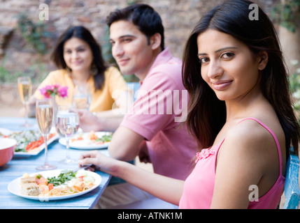 Young couple sitting with a mid adult woman at a dining table Stock Photo
