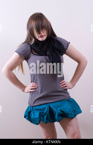 Busty woman hands on hips hair covering face wearing short blue skirt Stock Photo