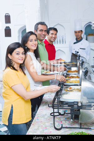 Portrait of two mid adult couples having lunch with a chef standing in the background Stock Photo