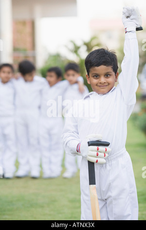 Portrait of a cricket player standing in a cricket field with other cricket players standing in the background Stock Photo