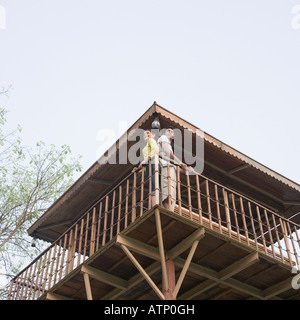 Low angle view of a young couple standing at the railing of a log cabin Stock Photo