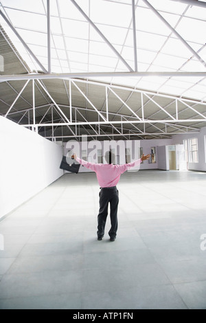 Rear view of a businessman standing with his arms outstretched and holding a briefcase in an entrance hall Stock Photo