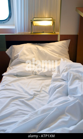 Unmade bed in tourist cabin Stock Photo