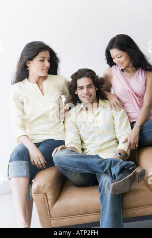 Young man sitting between two young women Stock Photo