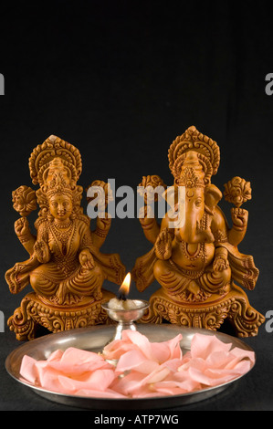 Close-up of an oil lamp and flower petals in front of Hindu gods Stock Photo