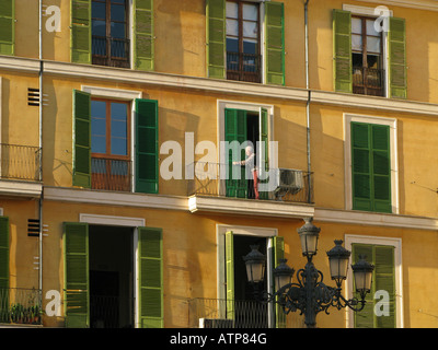 A man on one of the balconies on Plaza Major, Palma, Mallorca. An ornate street lamp is in the foreground Stock Photo