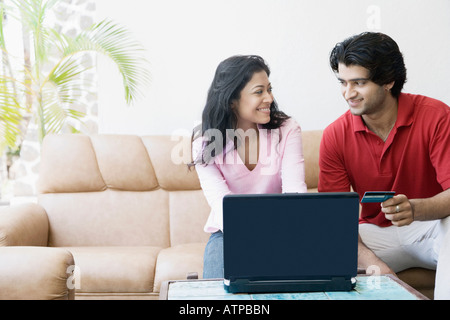 Young couple shopping online with a credit card and looking at each other Stock Photo
