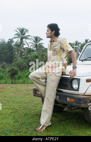 Young man leaning against a car and looking sad Stock Photo