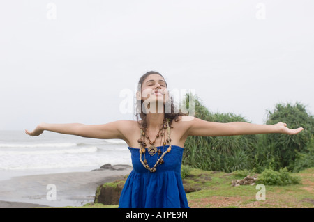 Young woman standing on the beach with her arms outstretched Stock Photo