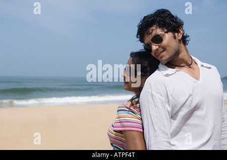 Close-up of a young couple standing back to back on the beach Stock Photo