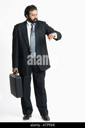 Businessman holding a briefcase and checking the time Stock Photo