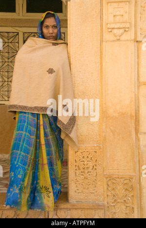 Young Indian woman in colorful sari standing by a pillar wrapped in a shawl. Stock Photo