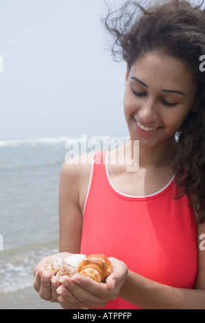 Close-up of a young woman holding seashells on the beach and smiling Stock Photo